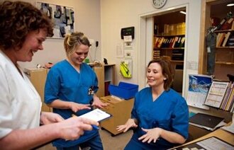 Bildet viser to sykepleiere som viser frem hender uten ringer.
