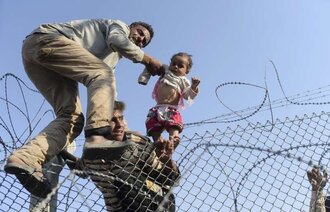Syriske flyktinger klatrer over piggtrådgjerde for å kommer til Tyrkia