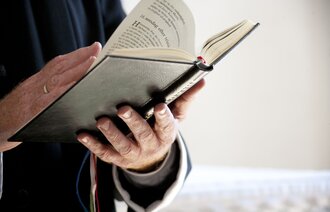 Prest som holder en salmebok i hendene