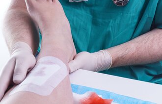 Viser helsepersonell som legger bandasje på en skadet fot