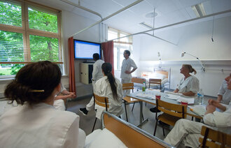 Bildet viser sykepleierstudenter ved Høgskolen i Oslo og Akershus inne i et undervisningsrom. Alle har uniformer på.