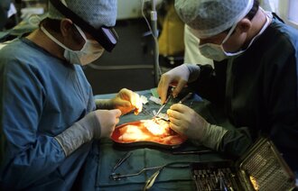 Bildet viser en nyretransplantasjon ved Rikshospitalet. To kirurger står over pasientens operasjonssår.