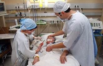 Bildet av to sykepleiere som behandler en pasient i seng