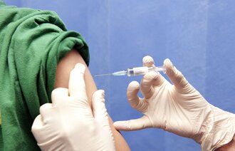 Bildet viser en vaksine som blir satt i en overarm.