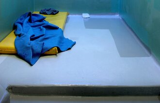Polstret celle med madrass på gulvet. Isolasjon i fengsel.