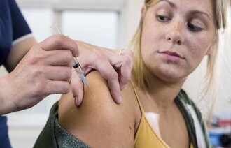 Bildet viser en ung jente som får hpv-vaksine av en sykepleier.