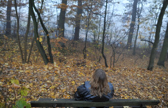 Kvinne sitter på benk i skogen. Illustrasjonsfoto: Frank May/NTB scanpix