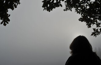 Bildet viser silhuetten av et menneske mot en grå himmel.