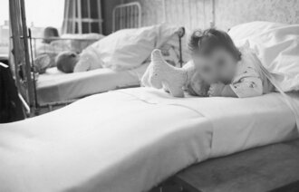Bildet viser et lite barn som ligger i en sykehusseng.