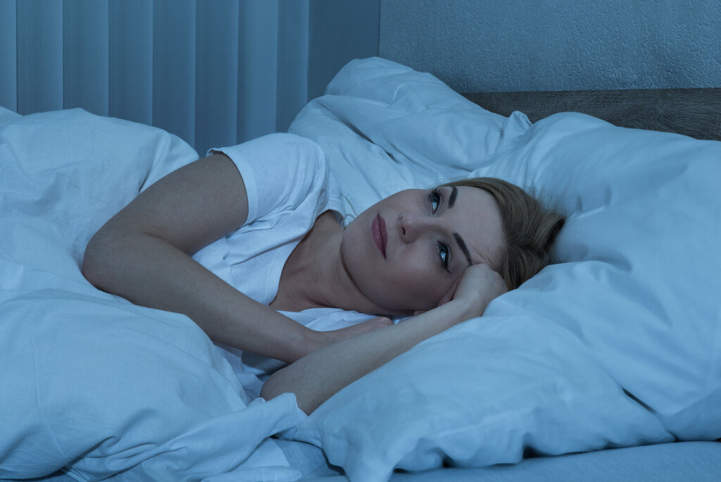 Bildet viser en dame som ligger i sengen og ikke får sove