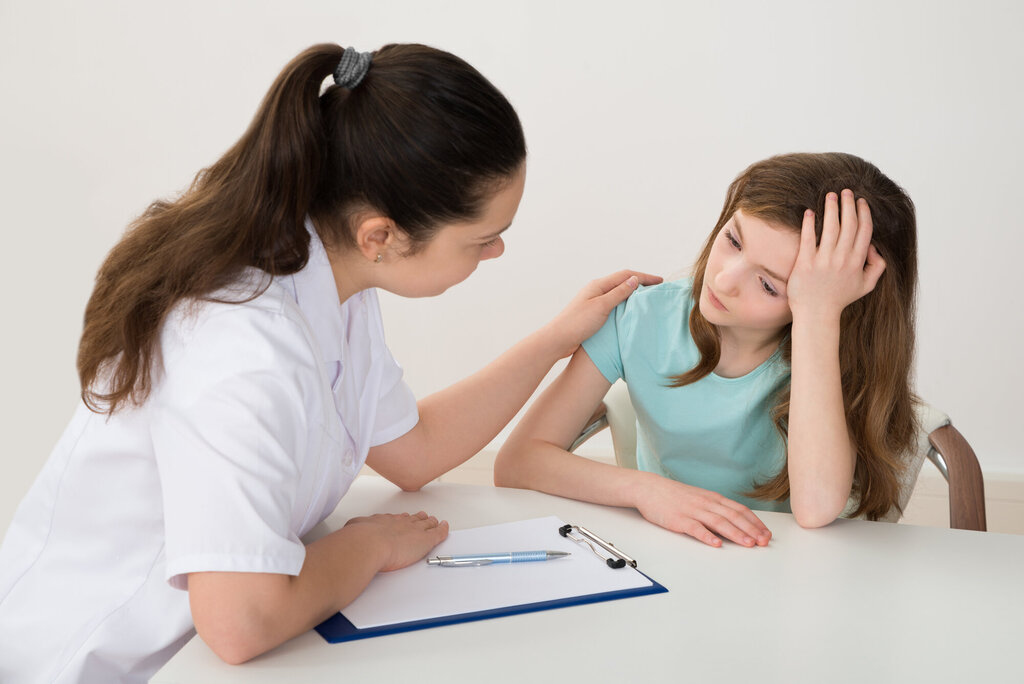 Bildet viser et helsepersonell som samtaler med en ung jente