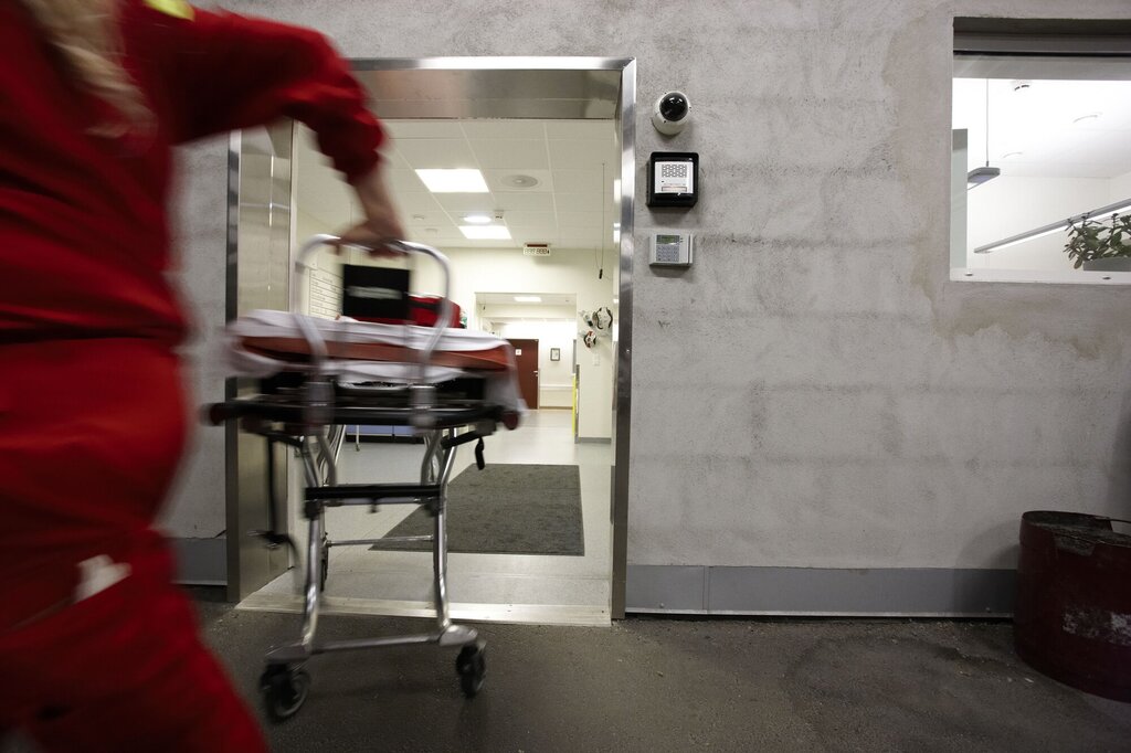 En mann i ambulanseuniform løper inn på sykehuset med en båre