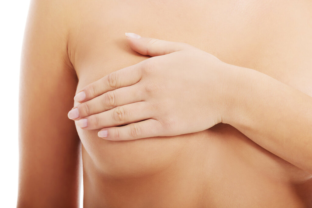 Bildet viser en naken kvinne som holder hånden over det ene brystet.