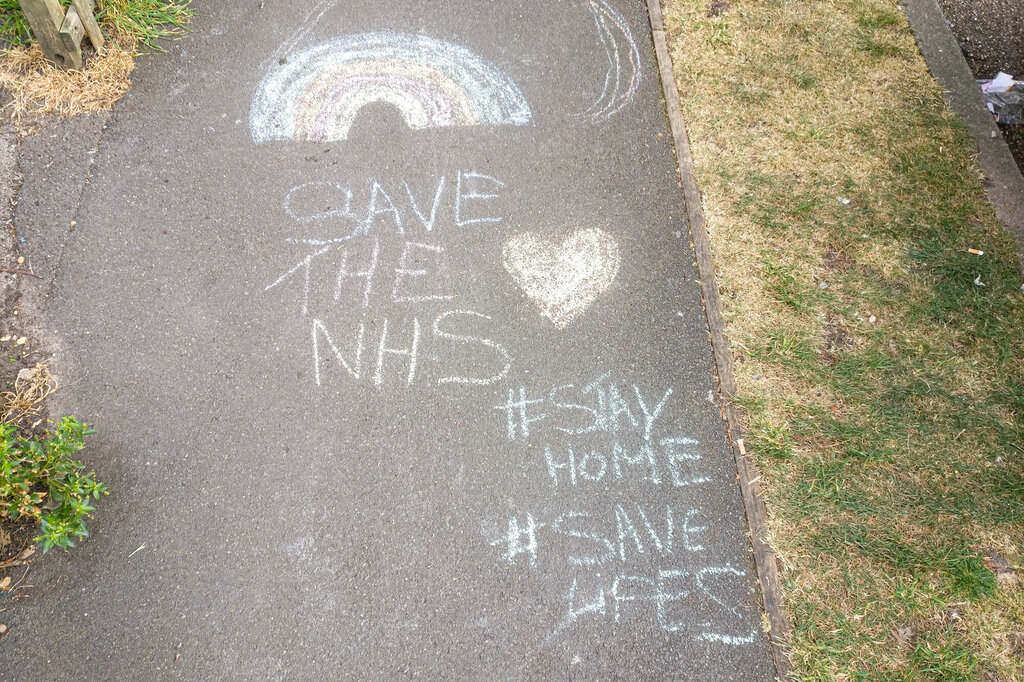 Bildet viser en krittegning på asfalten hvor det blant annet står Save the NHS