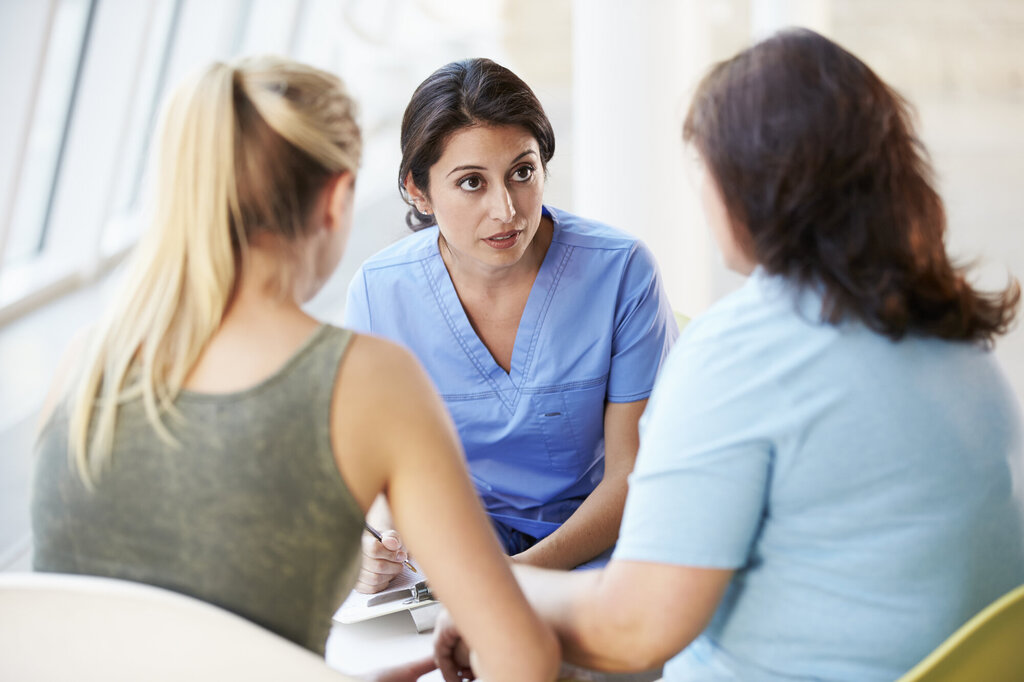 Sykepleier i samtale med mor og tenåringsdatter
