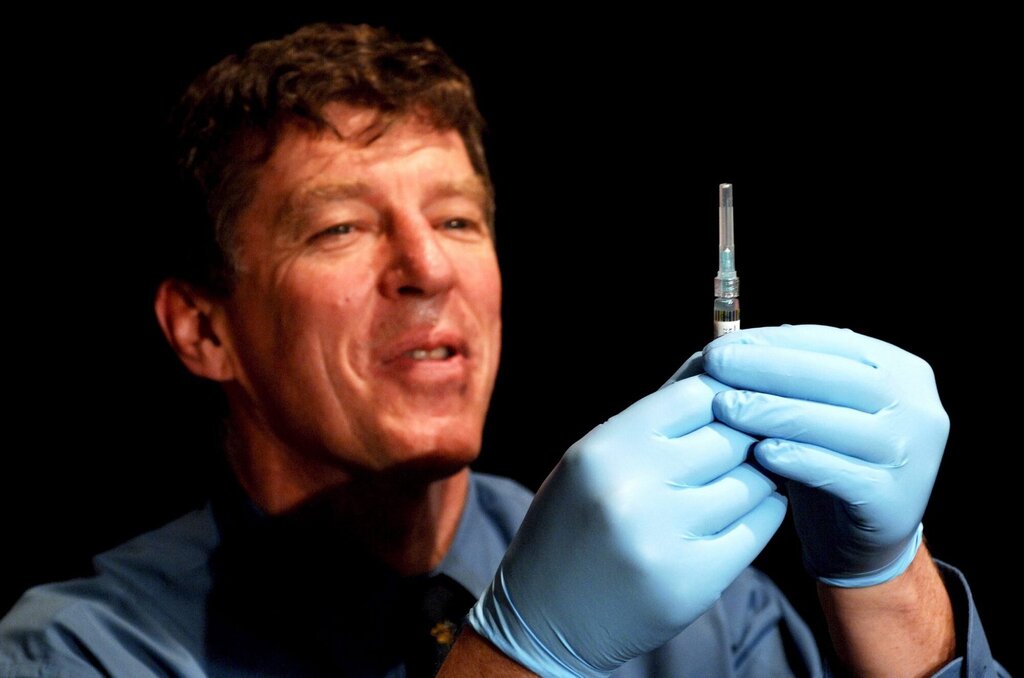 Bildet viser Ian Frazer som holder opp en vaksine.
