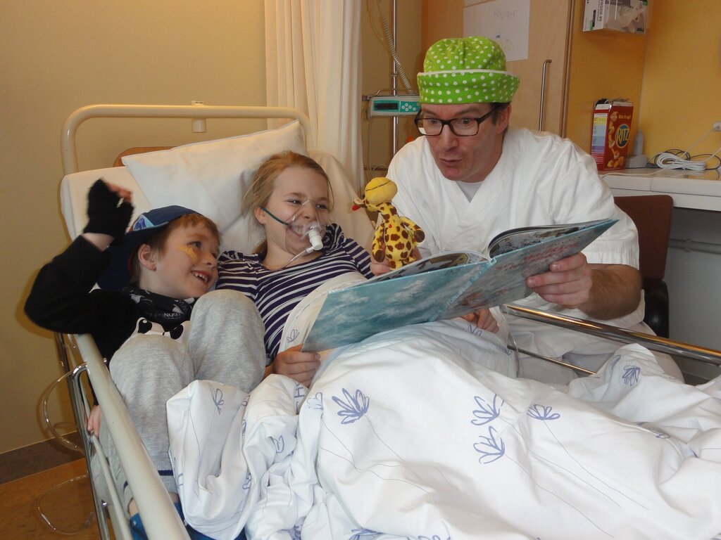 Bildet viser Mads Bøhle med to barn som ligger i en sykehusseng.