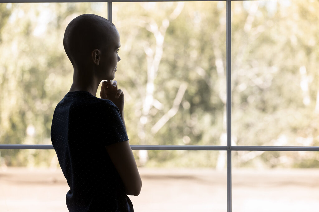Bildet viser en kvinne med kreft som titter ut av vinduet.
