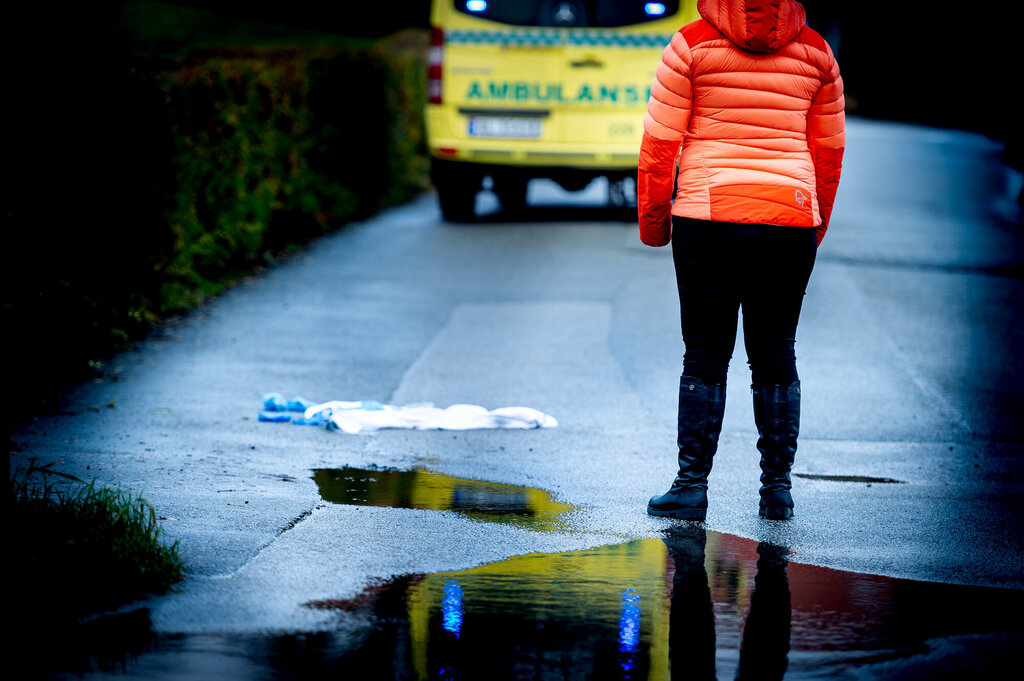 Kvinne står og ser mot ambulanse
