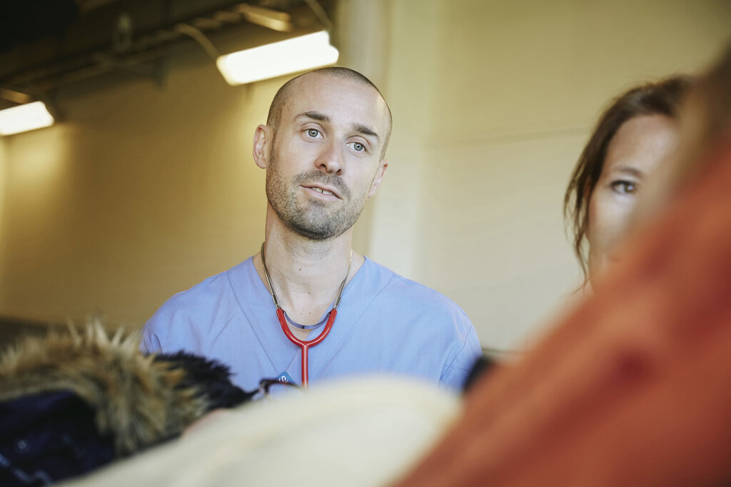 Bildet viser en sykepleier som ser med et godt blikk på en pasient vi bare skimter litt av kroppen til.