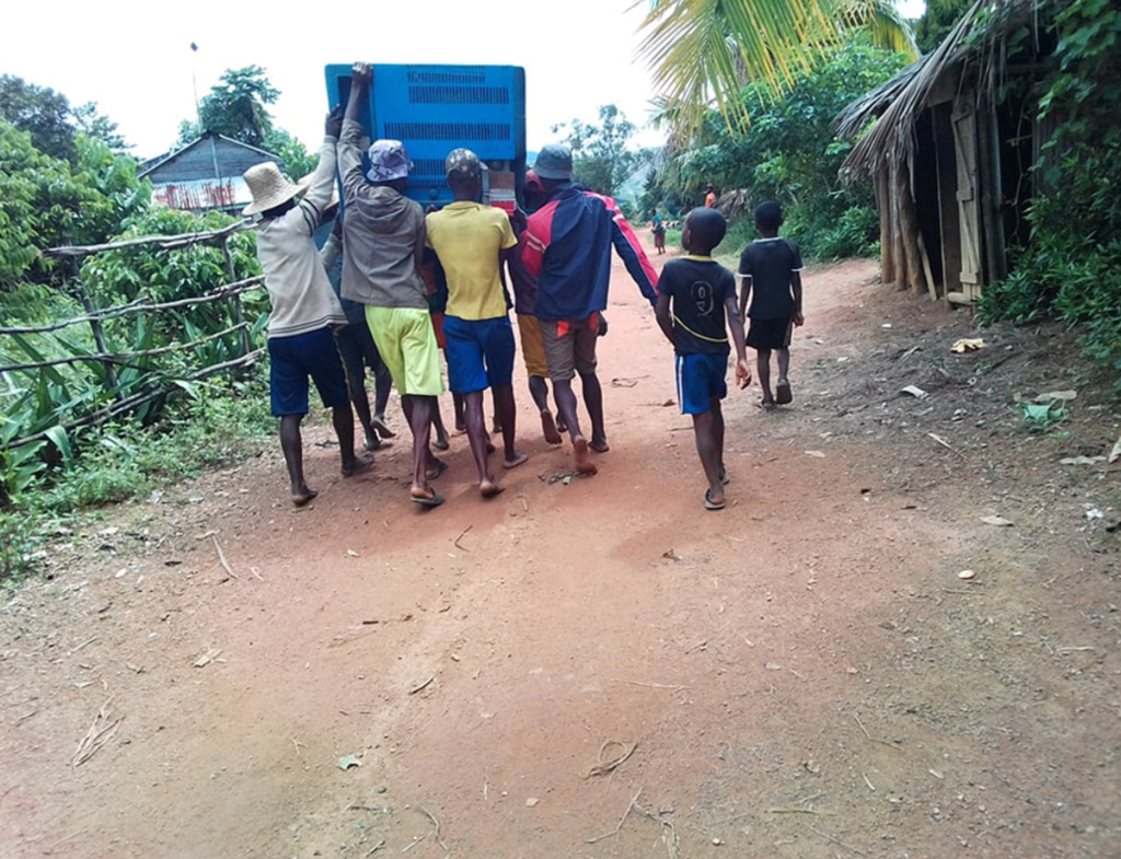 Bildet viser transport av vaksinar på Madagaskar, der kjølebagen med vaksinar transporteres av sju personer som bærer sammen
