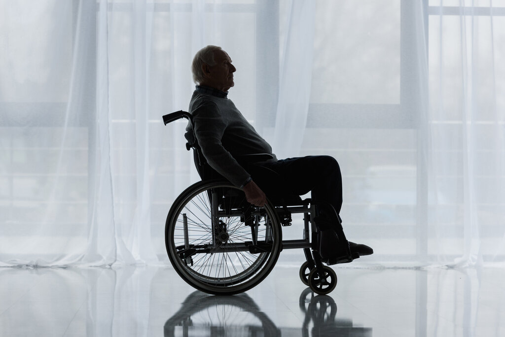Bildet viser en eldre mann som sitter i rullestol