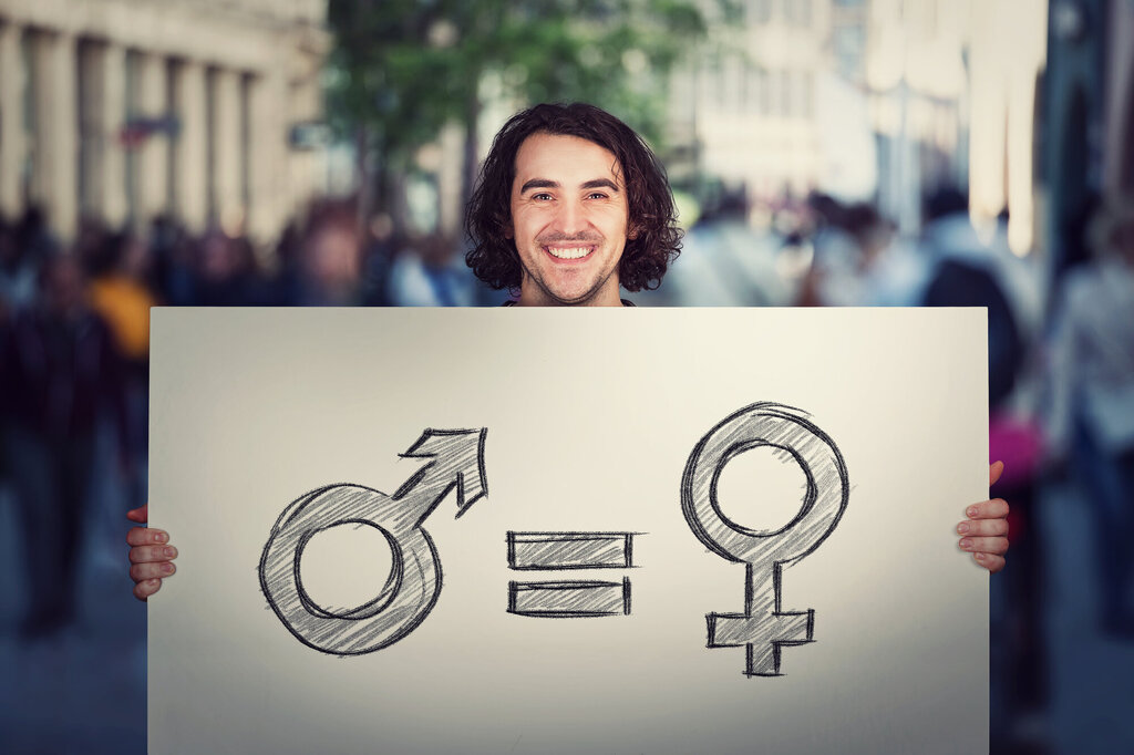 Bildet viser en man som holder opp en plakat som viser likhet mellom kjønnene