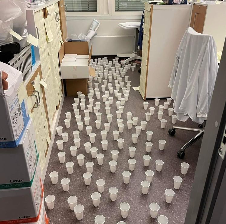 Bildet viser et kontor med mange hvite plastkopper, fylt med vann.