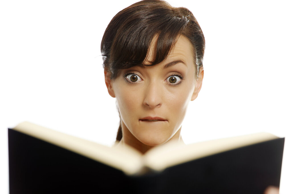 Bildet viser en kvinne som hever øyenbrynene over noe hun leser i en bok