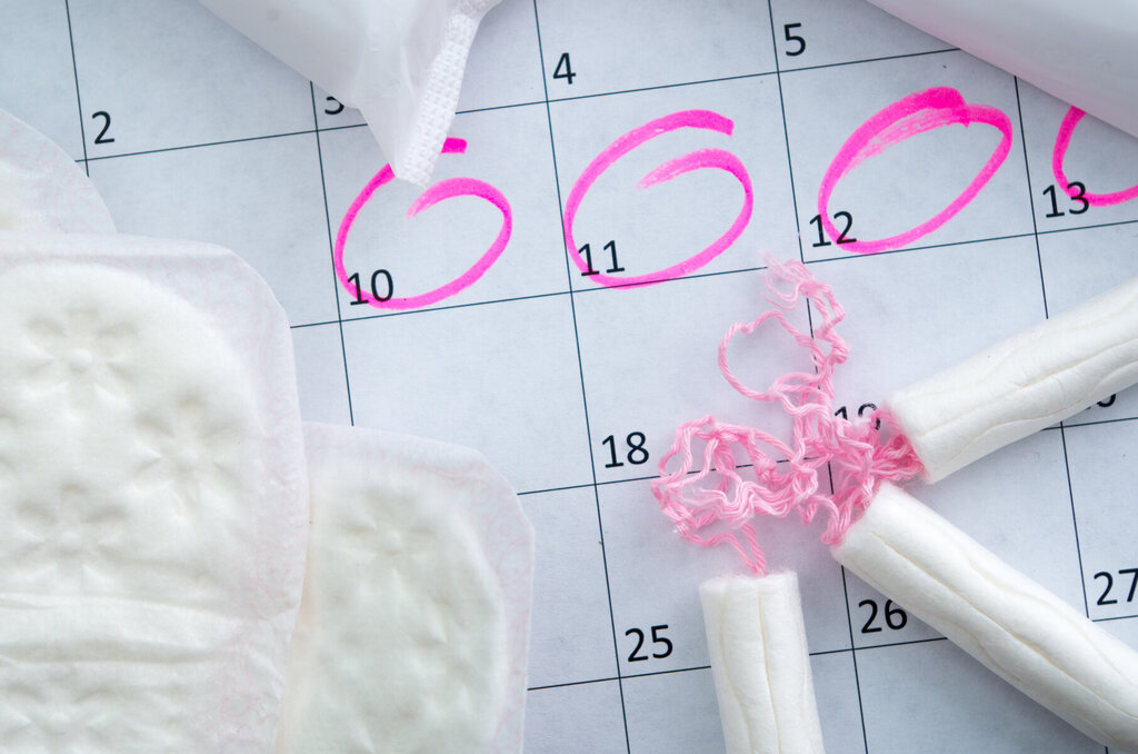 Kalender med tamponger og bind. Illustrere menstruasjonssyklus.