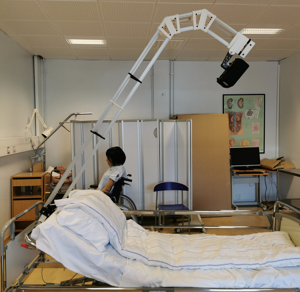  Bildet viser en projektor som er festet til en sykehusseng.