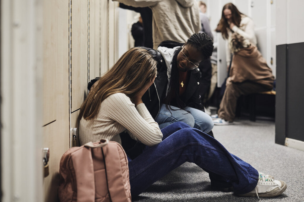 Bildet viser en skoleansatt som trøster en gråtende jente.