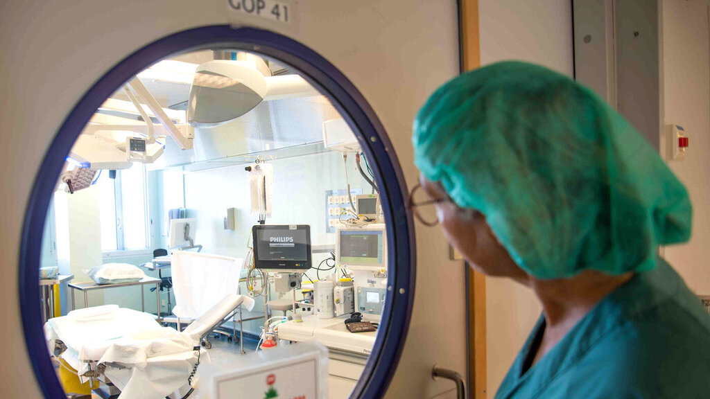 Bilde viser Marianne Jungersen som ser inn gjennom dørglasset til en operasjonsstue