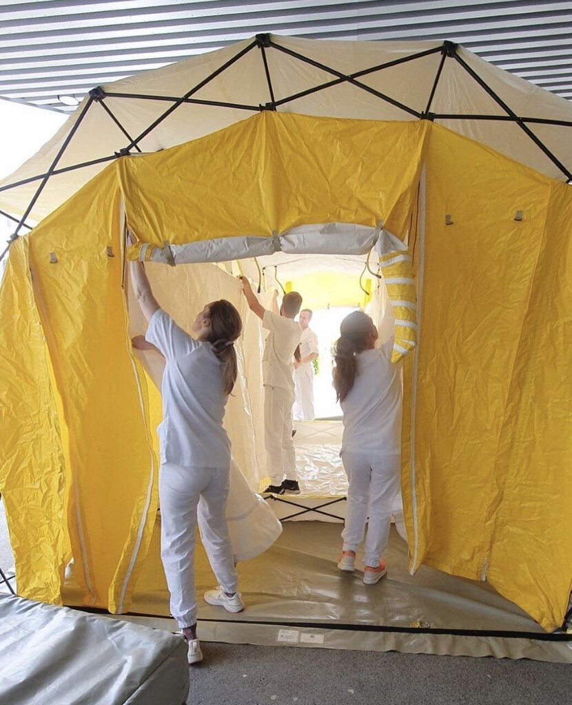 Bildet viser helsepersonell som setter opp et gult telt.