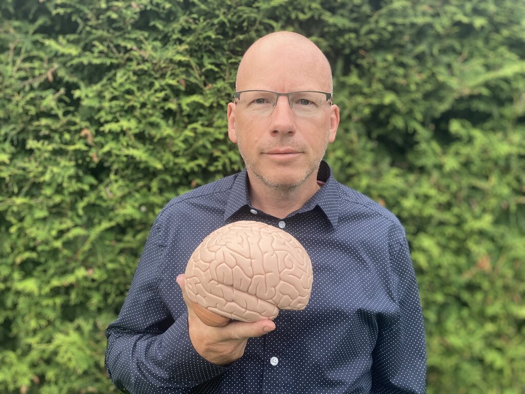 Bildet viser Tommy Skar som viser frem en plastmodell av en hjerne