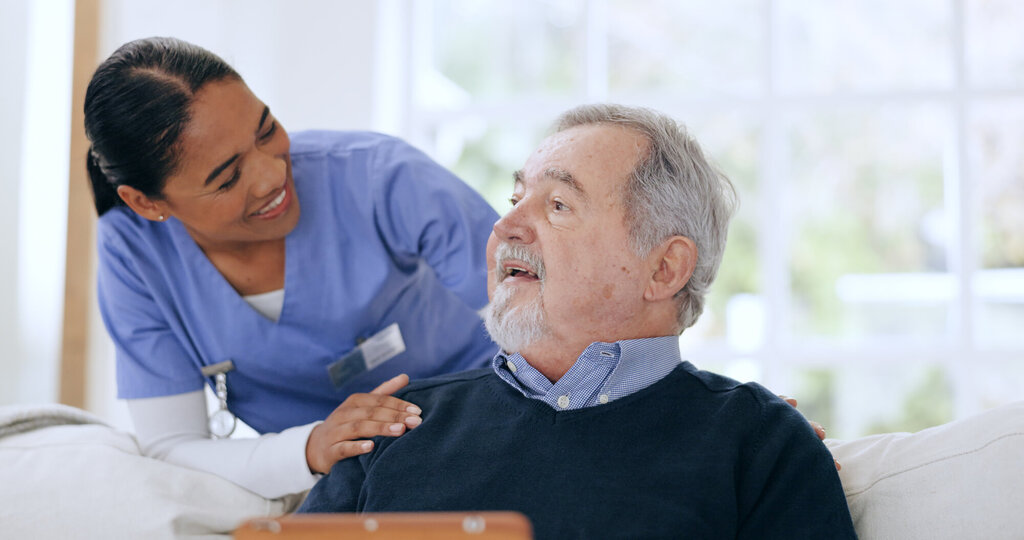 Bildet viser en melaninrik sykepleier som kommuniserer med en pasient