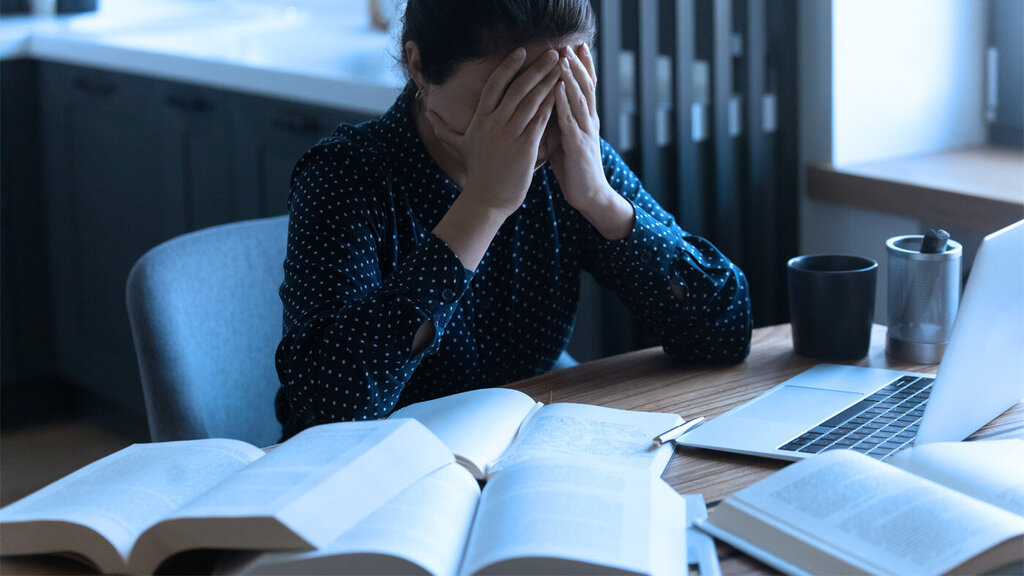 Bildet viser en student som hviler ansiktet i hendene.