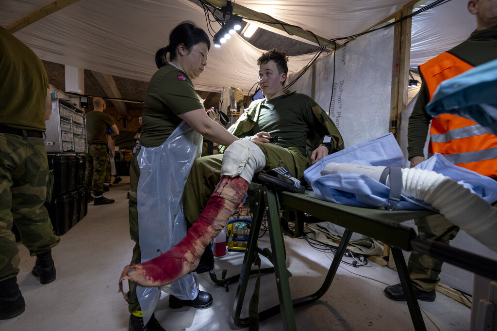 Bildet viser operasjonssykepleier som hjelper markør ned av operasjonsbordet.