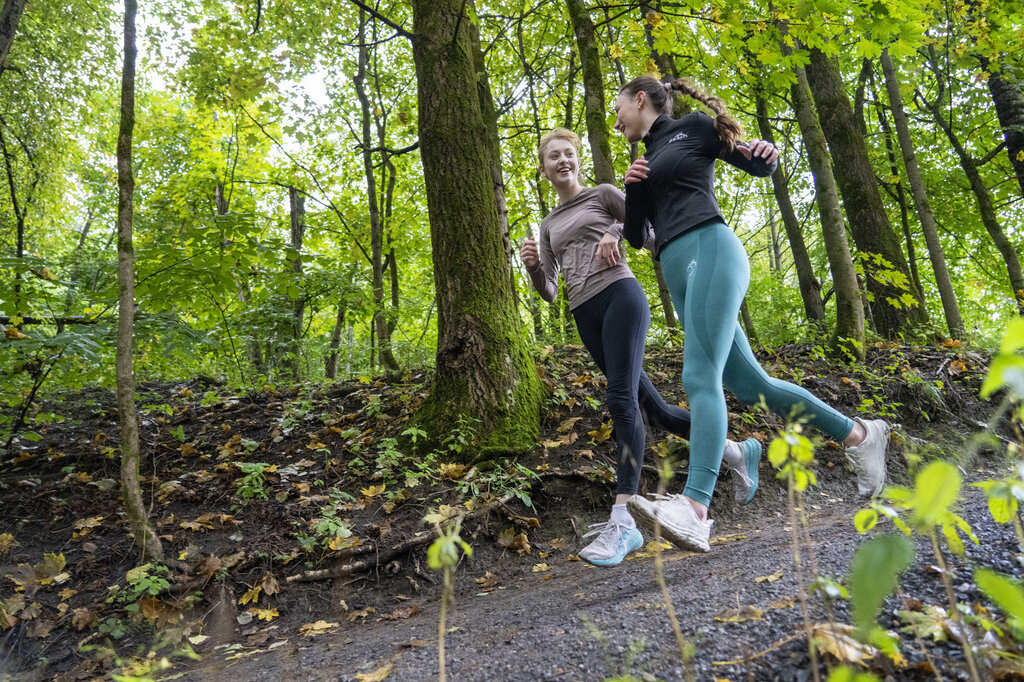 Bildet viser to unge kvinner som jogger i skogen.