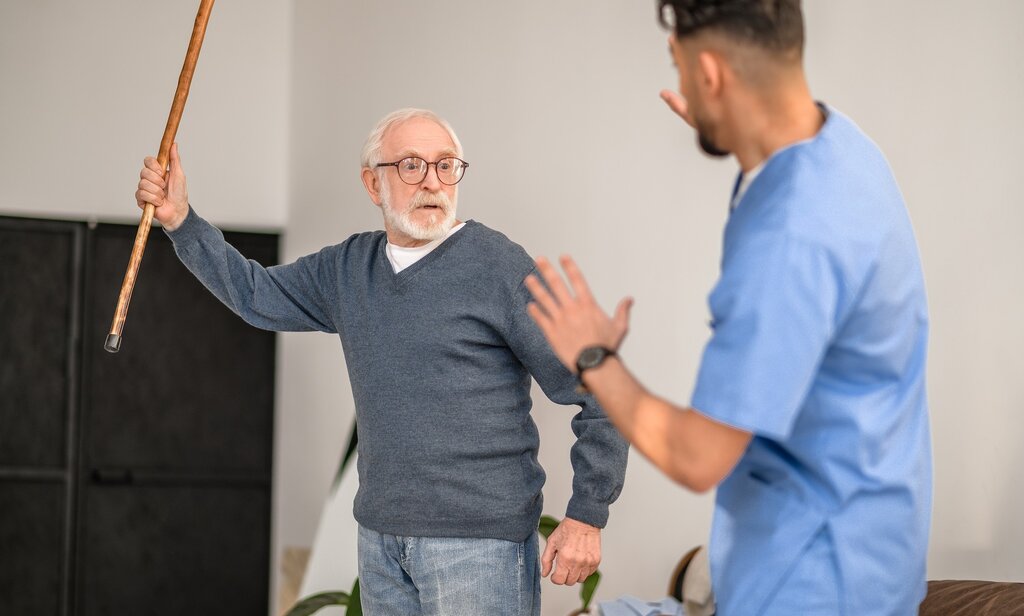 Bildet viser en aggressiv pasient som prøver å slå en sykepleier