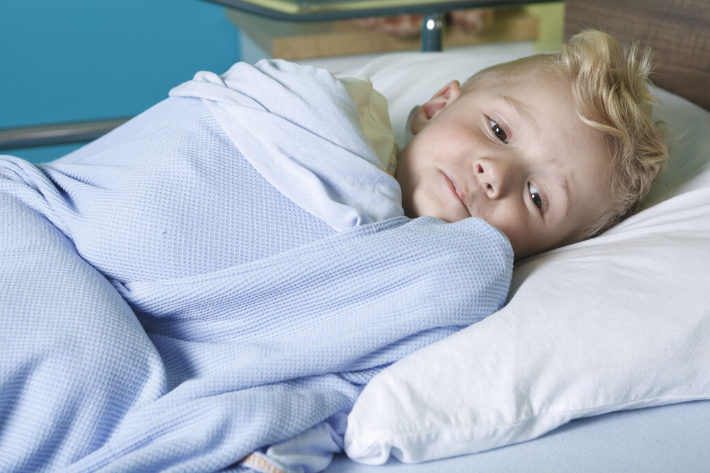 Bildet viser en syk, liten gutt i en sykehusseng.