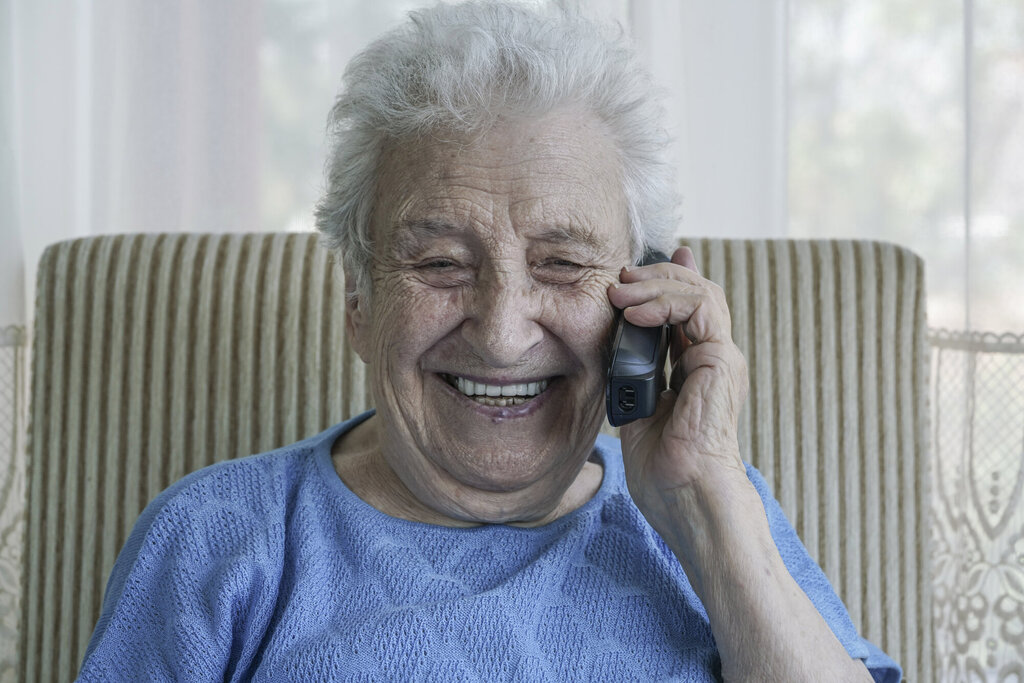 Bildet viser en fornøyd eldre kvinne som prater i telefonen