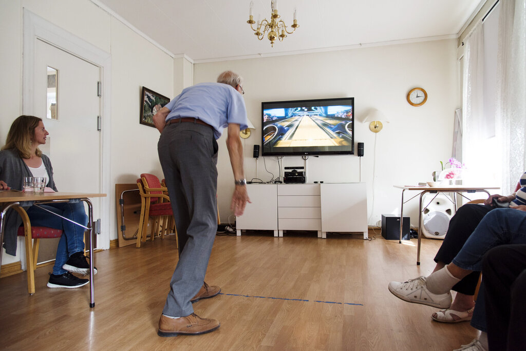 Bildet viser en eldre mann som spiller bowling på storskjerm ved hjelp av Kinect.