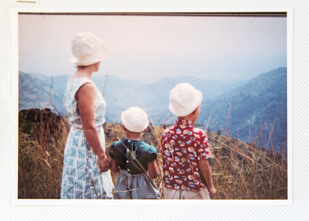 En mor og to barn ser utover et fjellandskap