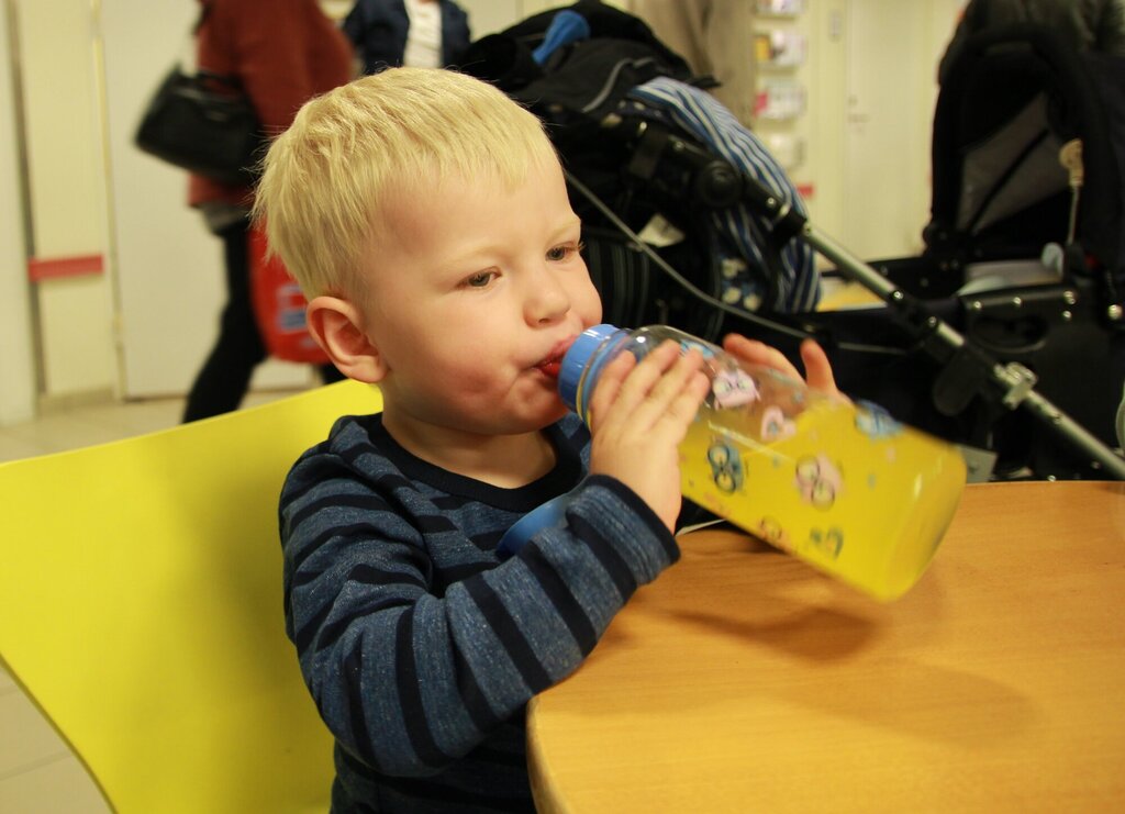 Sebastian drikker gul saft fra flaske.