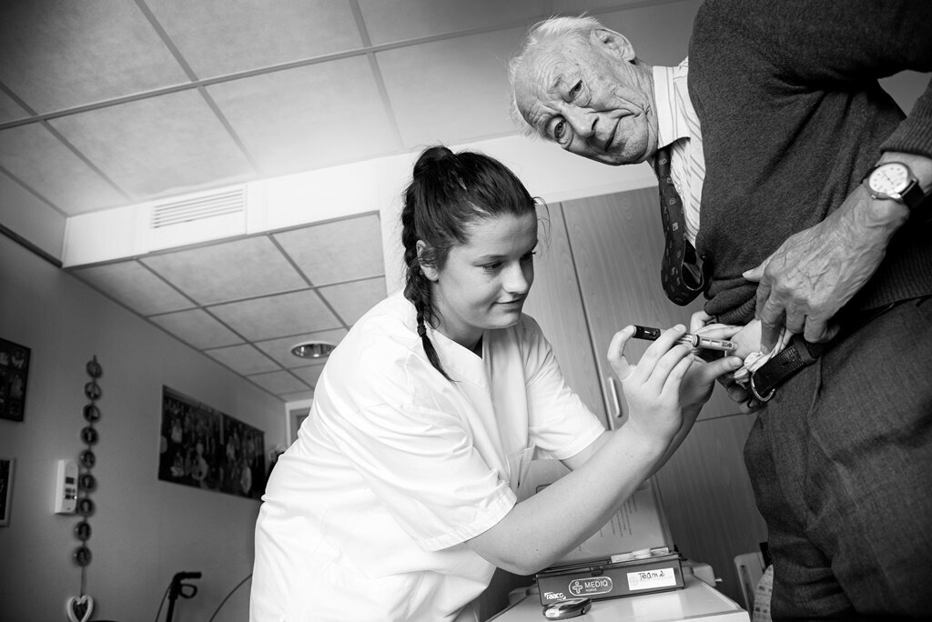 Sykepleier måler blodsukkeret til eldre mann på sykehjem