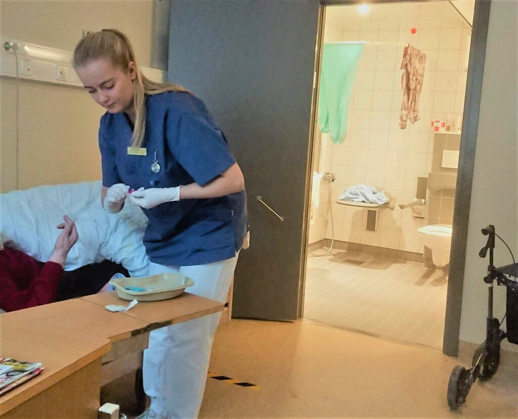 Bildet viser sykepleierstudent Stine Sundberg som har praksisplass på et eldrehjem. Hun hjelper en sengeliggende beboer.