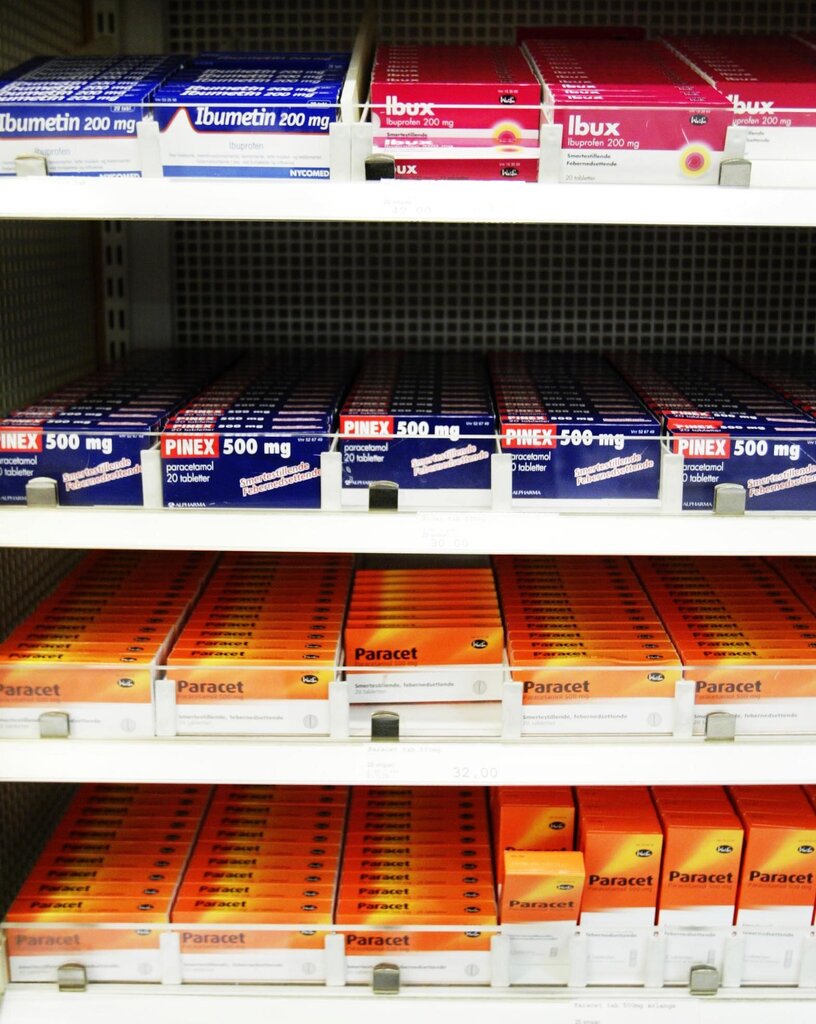 Bildet viser pakninger med smertestillende tabletter, som Paracet og Ibux, i en hylle