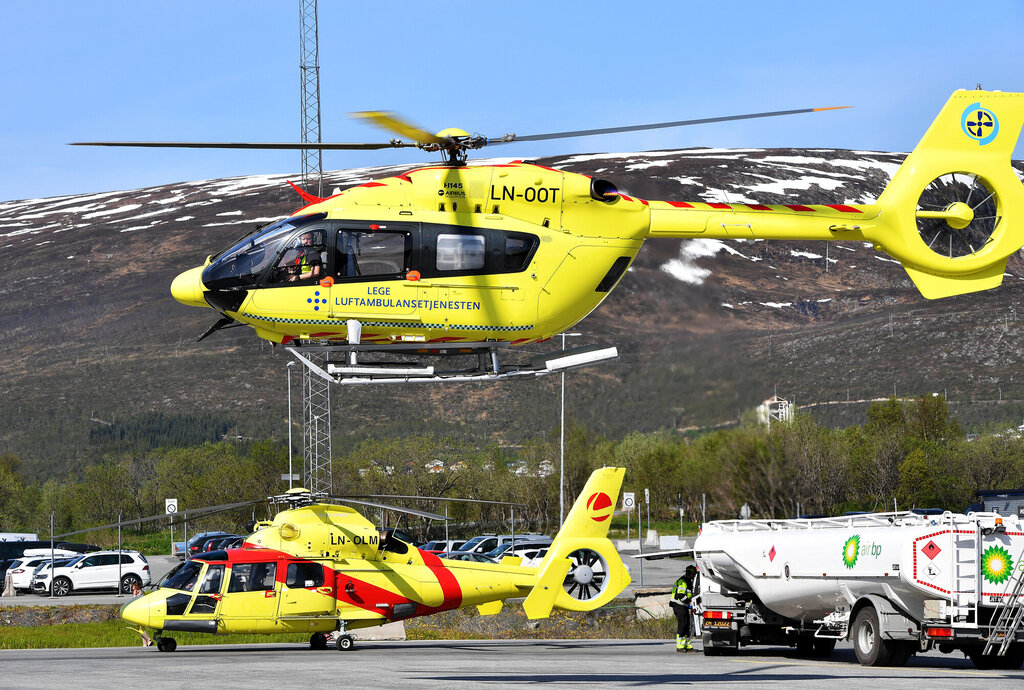 Bildet viser et ambulansehelikopter som er i ferd med å lette, og et som står på bakken i bakgrunnen