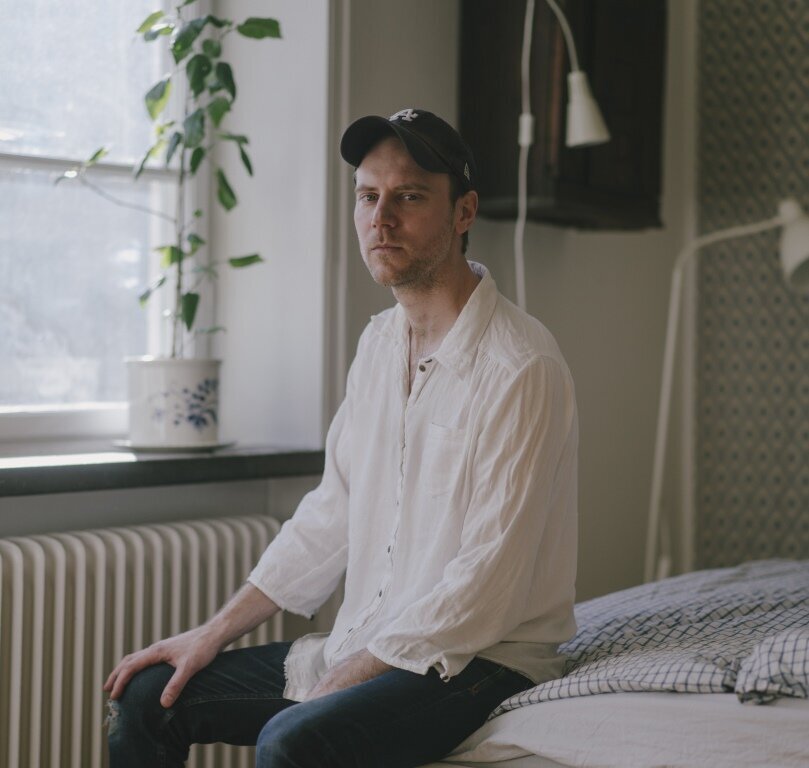 Bildet viser Tom Malmquist som sitter på en seng.